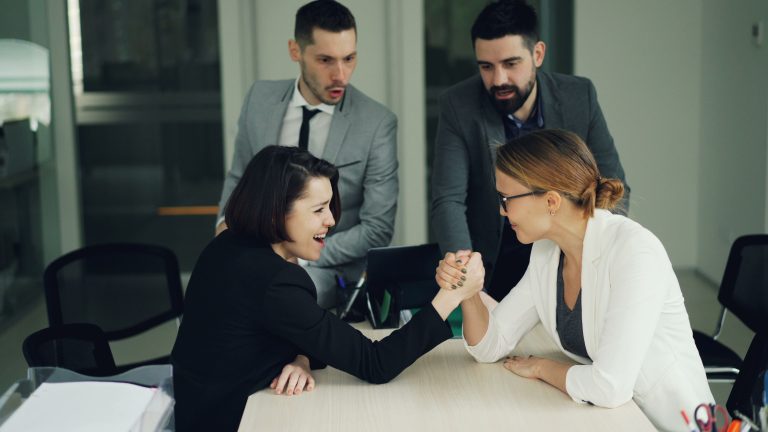 Colleagues engaging in a spirited arm wrestling contest at work, showcasing teamwork and competition
