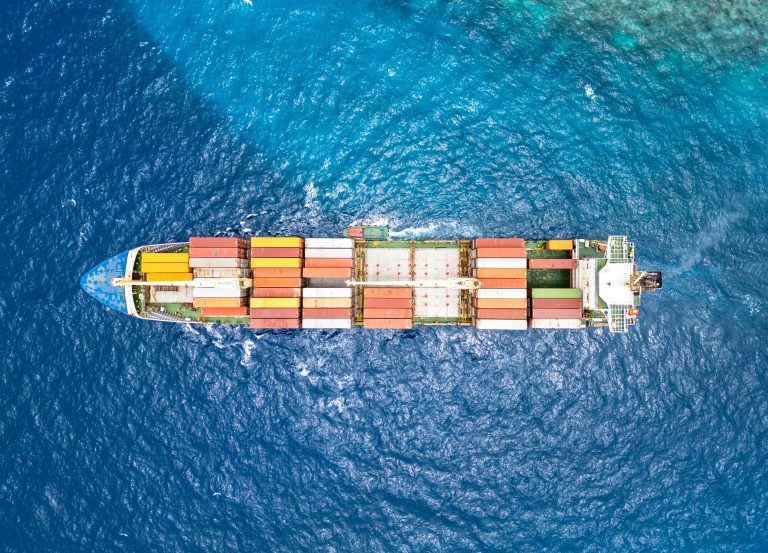 Container ship carrying cargo across blue ocean water, seen from directly above