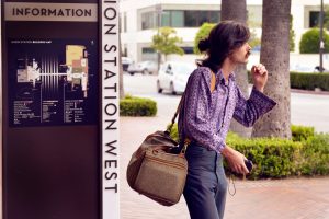 Stylish young man with bag waits at Union Station in Los Angeles, embodying urban exploration