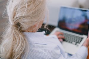 A senior woman with white hair using a laptop in a casual home setting