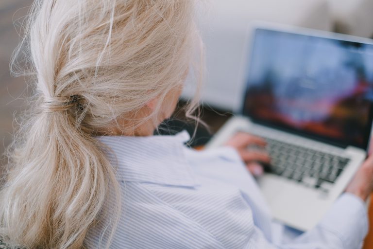 A senior woman with white hair using a laptop in a casual home setting