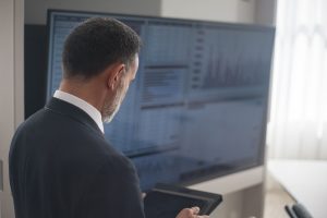 Professional analyzing stock markets on a digital tablet in a modern office setting
