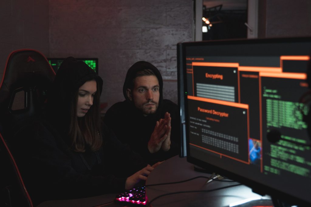 Cybersecurity experts in hoodies analyzing encrypted data on computer screens in an indoor setting