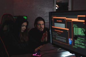 Cybersecurity experts in hoodies analyzing encrypted data on computer screens in an indoor setting
