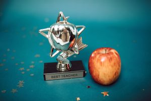Silver star-shaped trophy with apple on a blue background for teacher appreciation