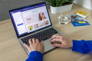 Hands typing on a laptop showing an e-commerce website in a modern office setting