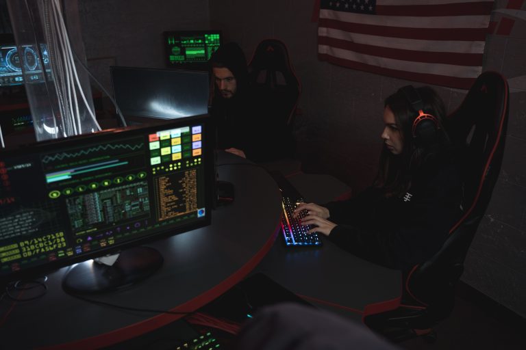 Cybersecurity professionals working on computer systems, focusing on data protection in a dimly lit room