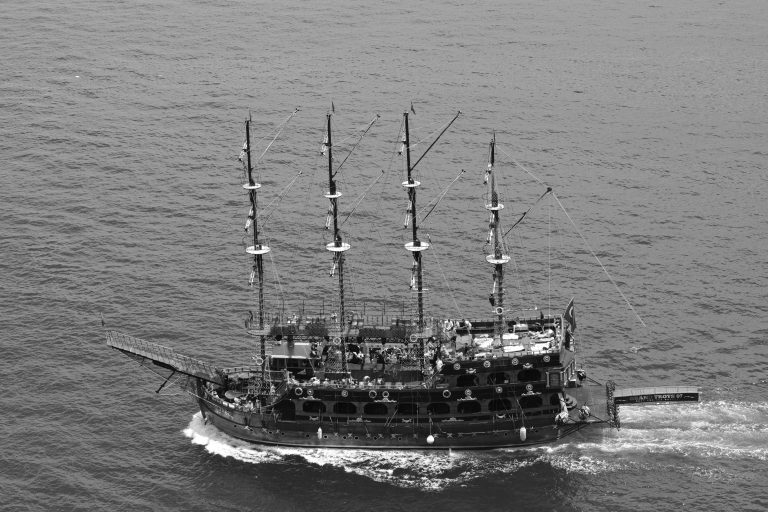 Aerial black and white photo of a pirate ship sailing the ocean, showcasing nautical adventure