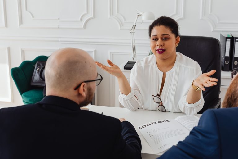 A businesswoman leads a meeting discussing a contract in a modern office setting