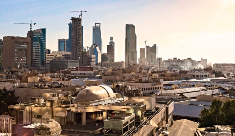 Skyline of Riyadh, Saudi Arabia featuring modern skyscrapers and construction cranes at sunset