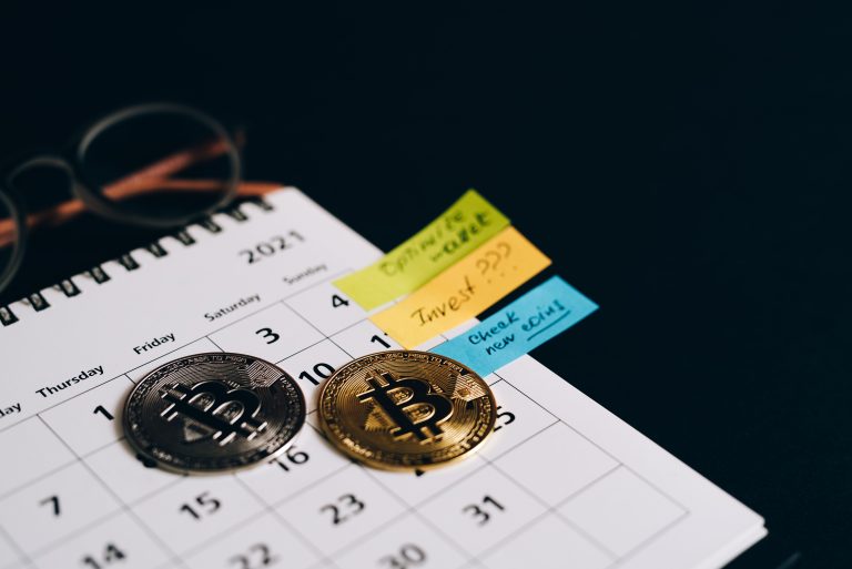 Bitcoin coins placed on a calendar with sticky notes for investment planning