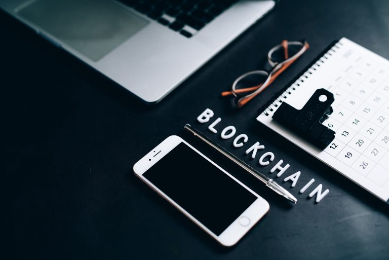 Flat lay of a modern digital workspace with blockchain theme, featuring a smartphone and calendar