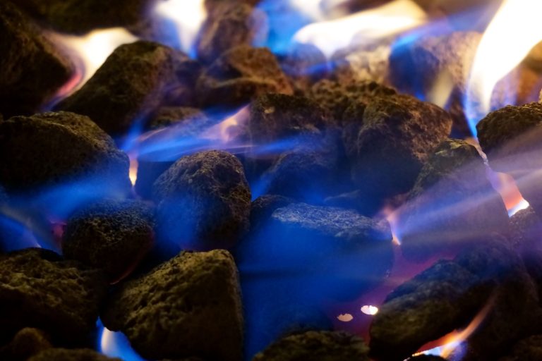 A close-up view of burning charcoal with vibrant blue flames, capturing the warmth and texture