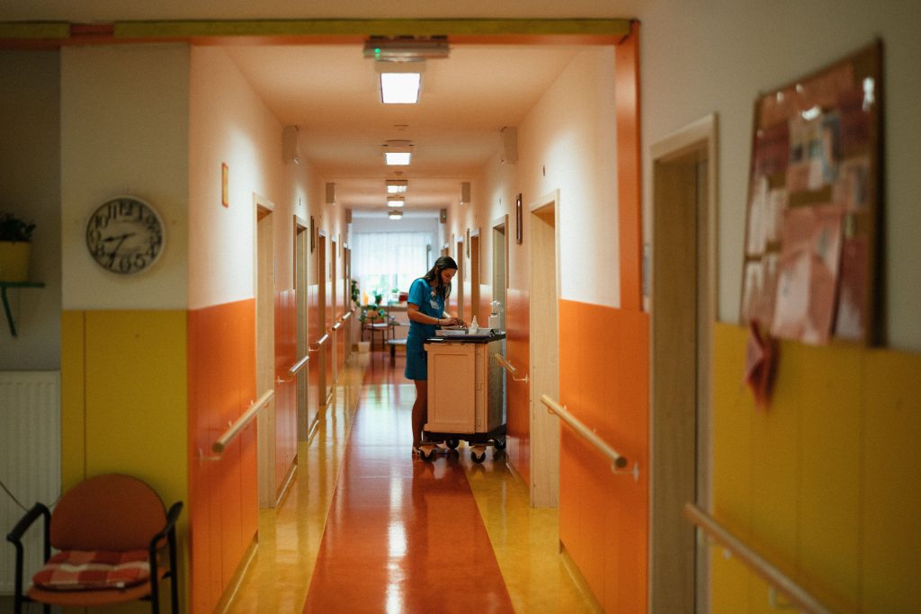 A nurse works at a cart in a brightly colored hospital corridor