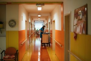 A nurse works at a cart in a brightly colored hospital corridor