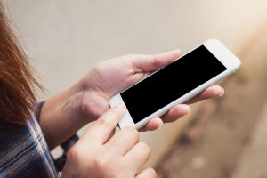 Hands holding a smartphone outdoors
