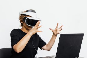 Adult using VR headset and laptop for a virtual reality experience indoors