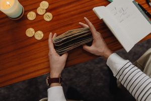 Close-up of a person organizing money with cryptocurrency coins on a wooden table, symbolizing modern finance